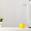 yellow ceramic mug beside gray aluminum iMac